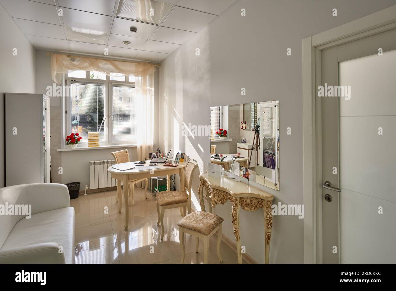 Interior of a bright room with a comfortable sofa, and a mirror by a light-colored wall Stock Photo