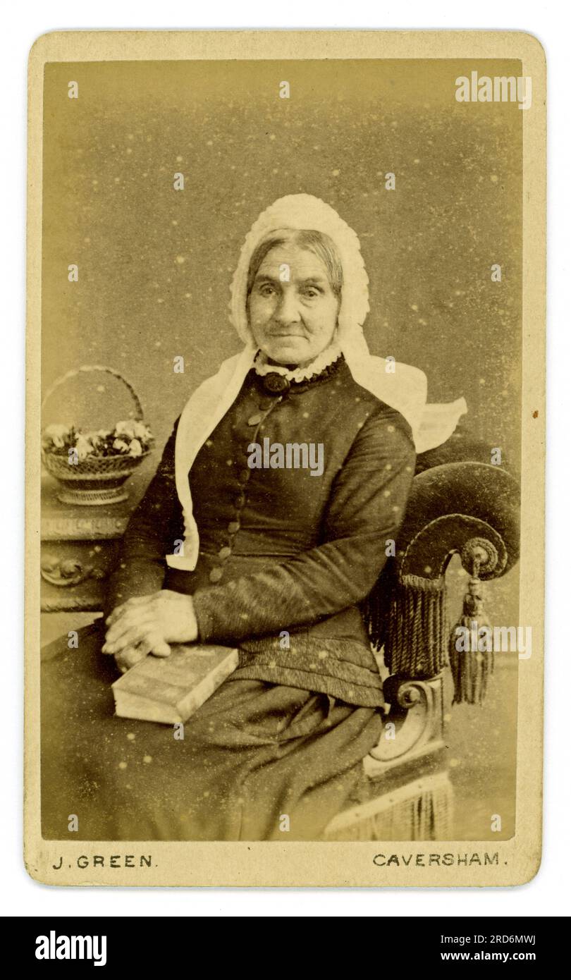 Original 1880's Victorian CDV (carte de visite or visiting card) portrait of an elderly woman seated, wearing a white lace cap and holding a book from the studio of Joseph Green, Bridge St Caversham, Reading, Berkshire, England, U.K. From 1881. Circa 1882 / 1883.. Stock Photo