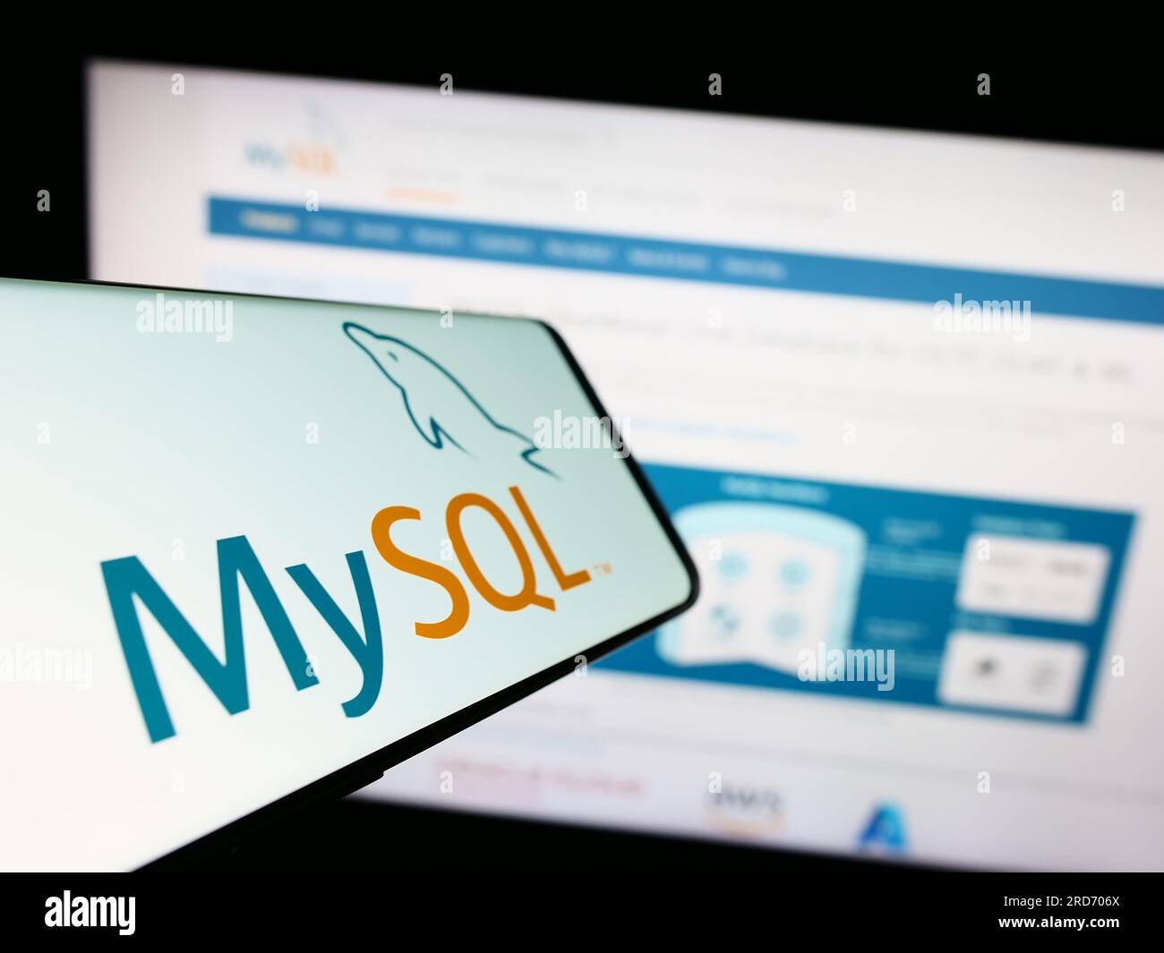 Smartphone with logo of relational database management system MySQL on screen in front of website. Focus on center of phone display. Stock Photo