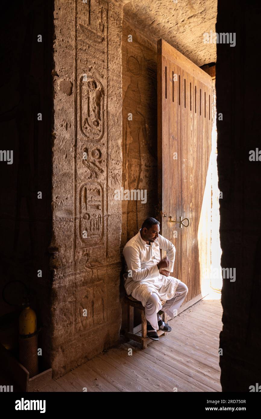 A man sits by the entrance door to the temple at Abu Simbel in Egypt. Stock Photo