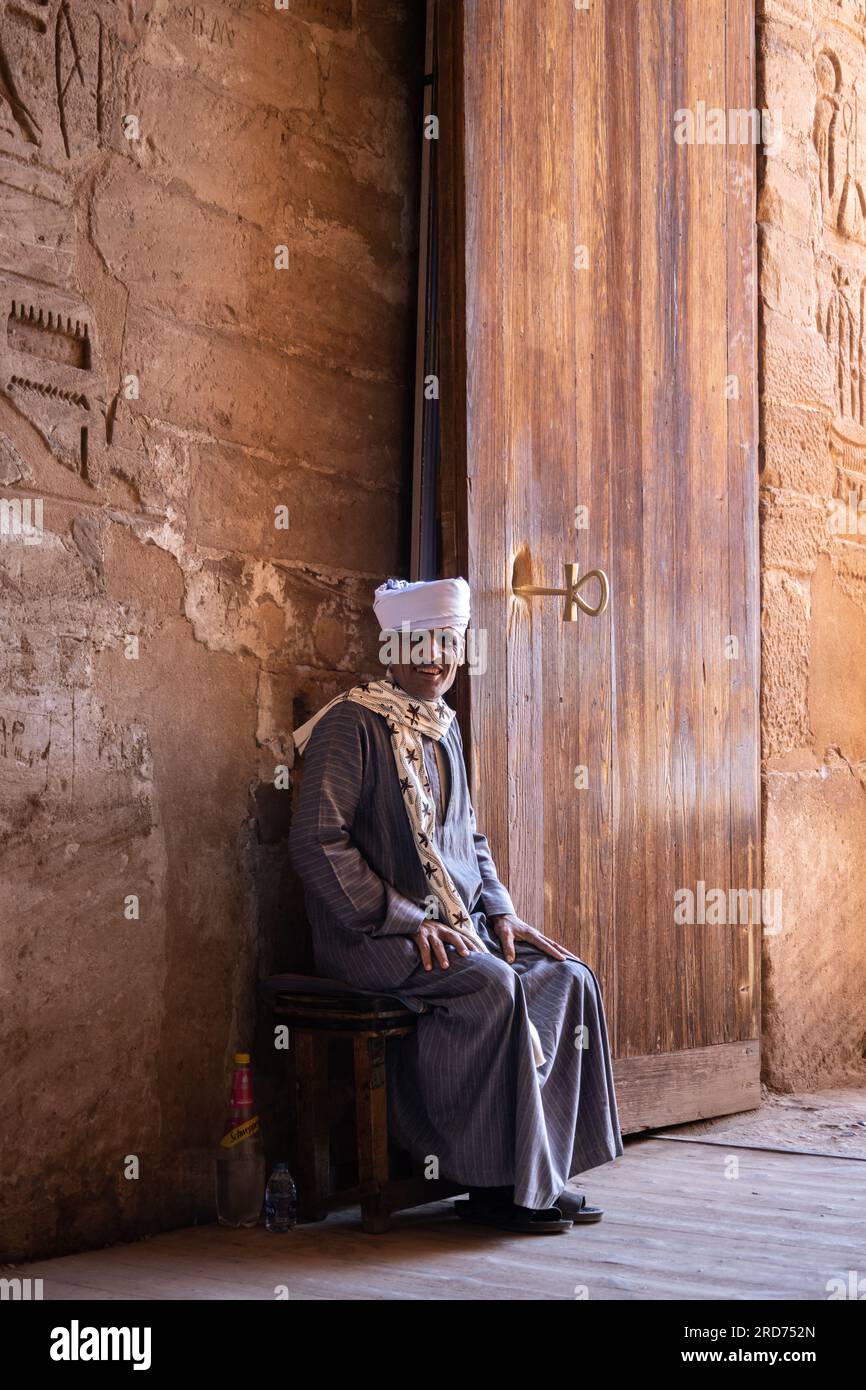 A man sits by the entrance door to the temple at Abu Simbel in Egypt. Stock Photo