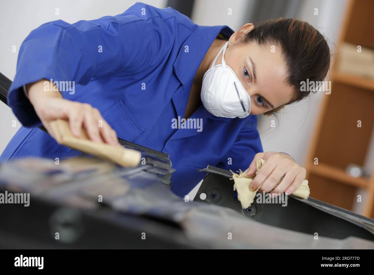 female mechanic sanding a vehicle part Stock Photo