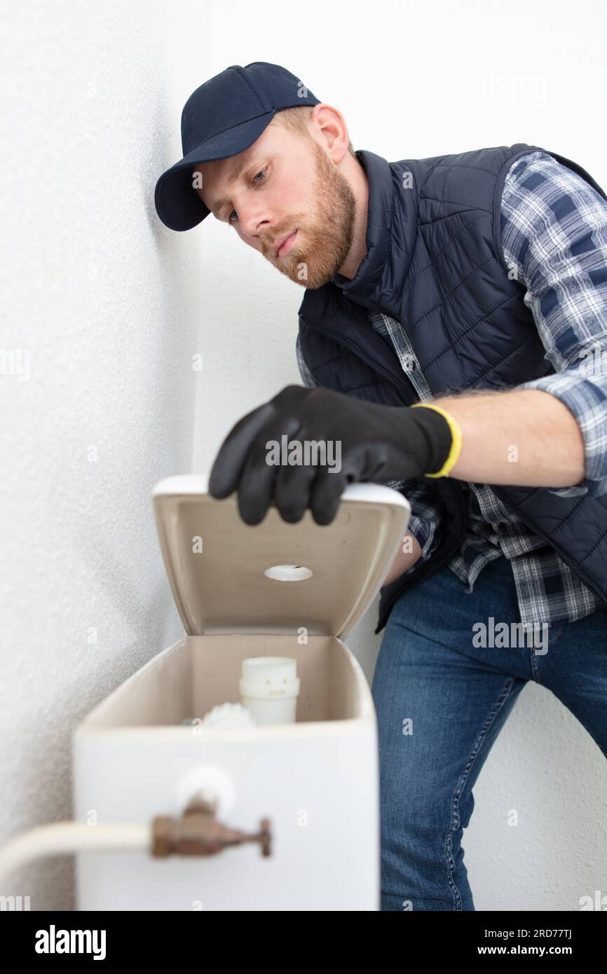 young plumber repairing toilet valve Stock Photo Alamy
