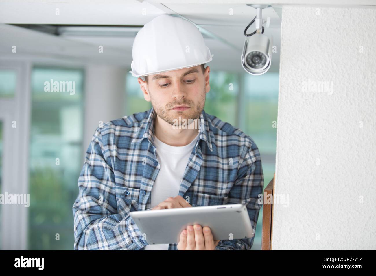 contractor using tablet by security camera Stock Photo