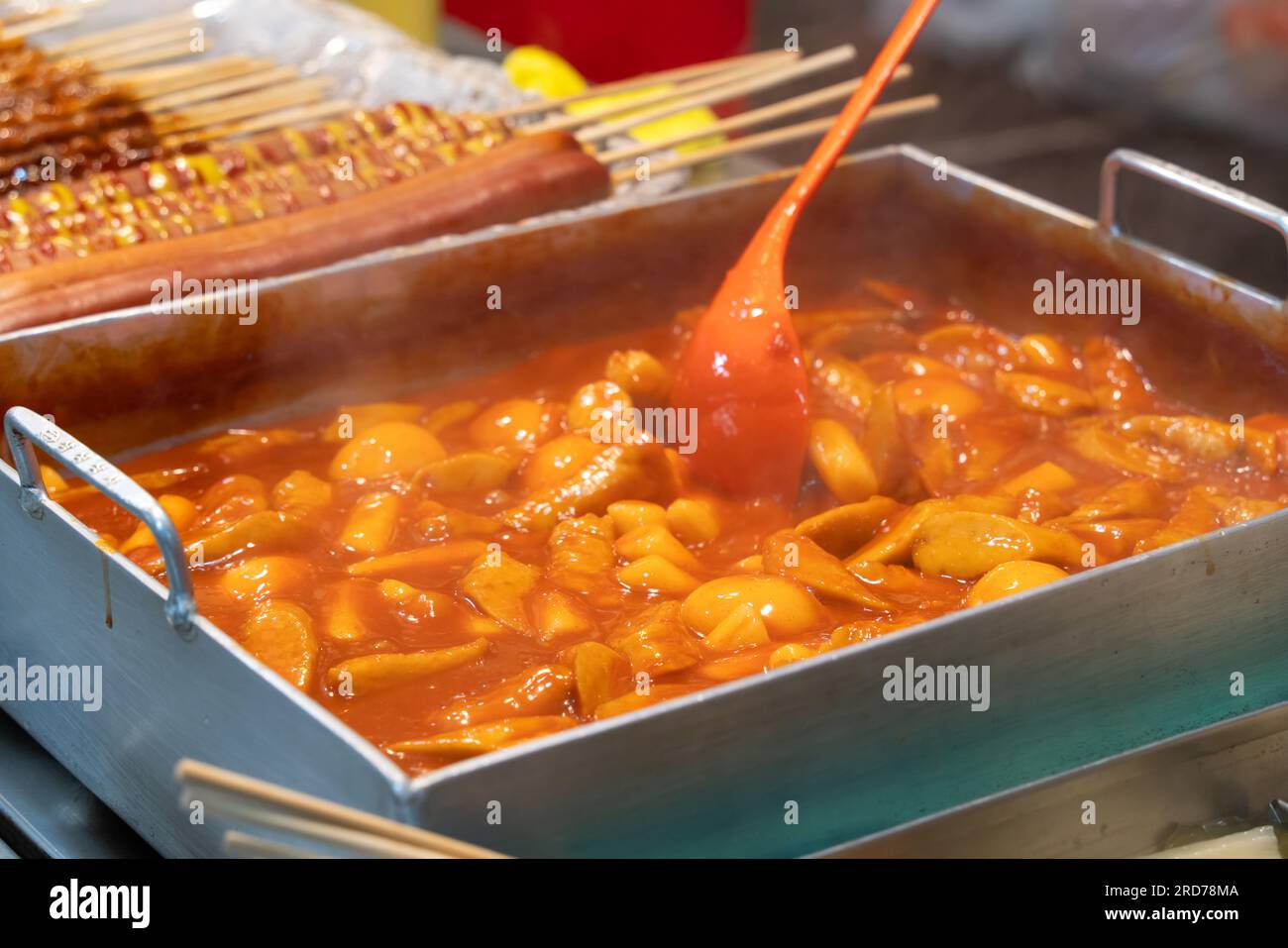 Delicious Korean cuisine Tteokbokki, tasty spicy rice cake with sausages, eggs in market for street food snacks. Stock Photo
