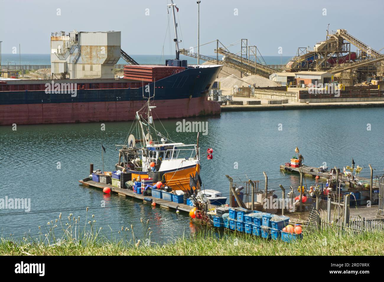 Fishing boat and large bulk carrier ship in port at Shoreham Harbour, West Sussex, England. No people. No logos. Stock Photo