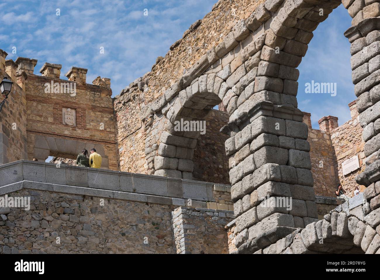 Spain tourism, rear view of a young couple in conversation beside the magnificent 1st Century Roman aqueduct in Segovia, Spain Stock Photo