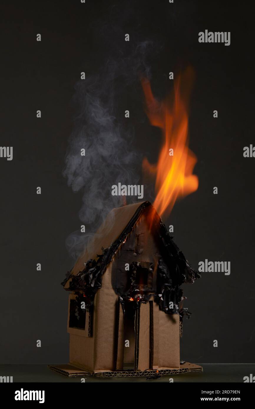 Burning cardboard house with dark background Stock Photo