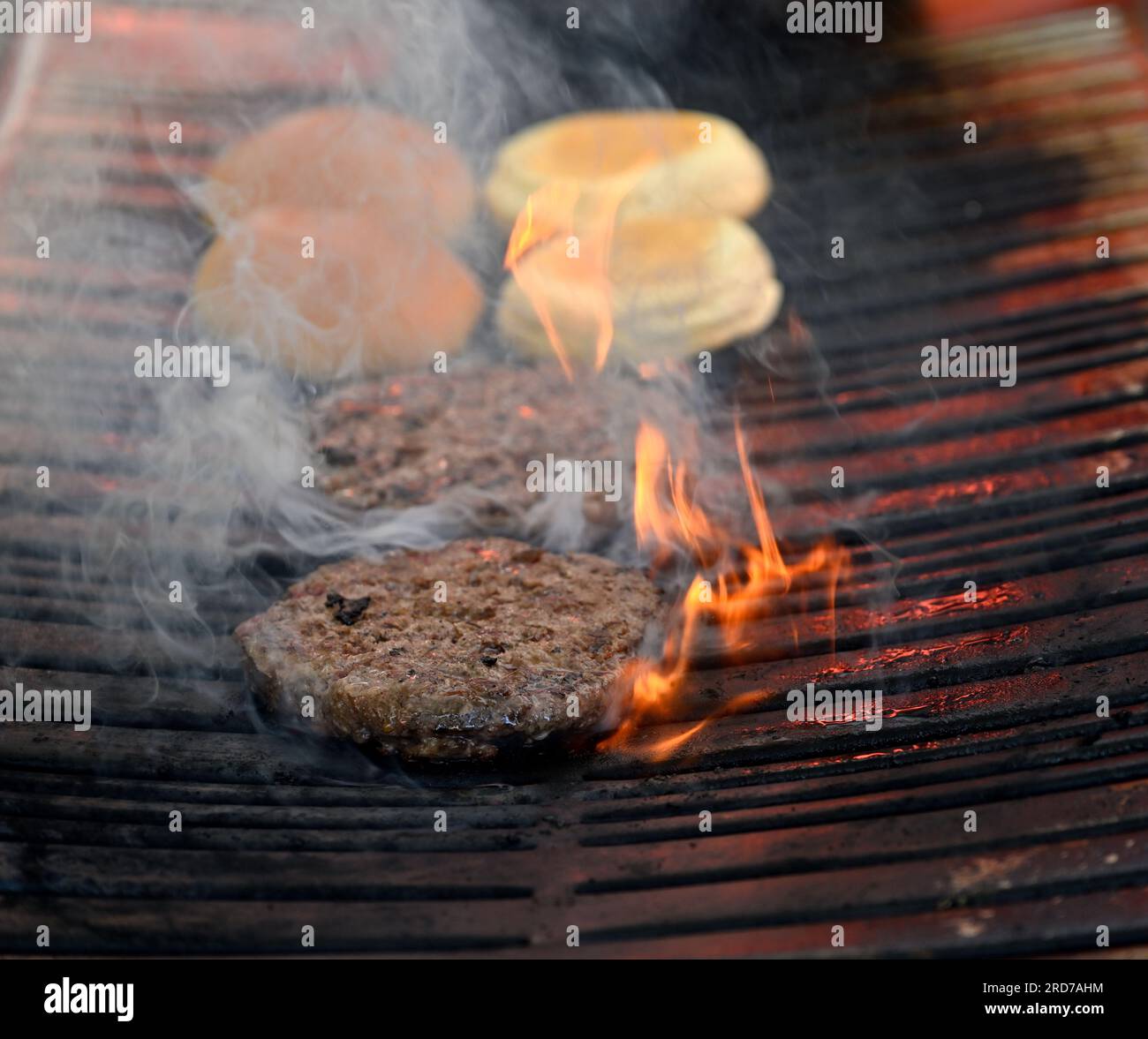 Burgers cooking on charcoal BBQ grill with flames Stock Photo Alamy