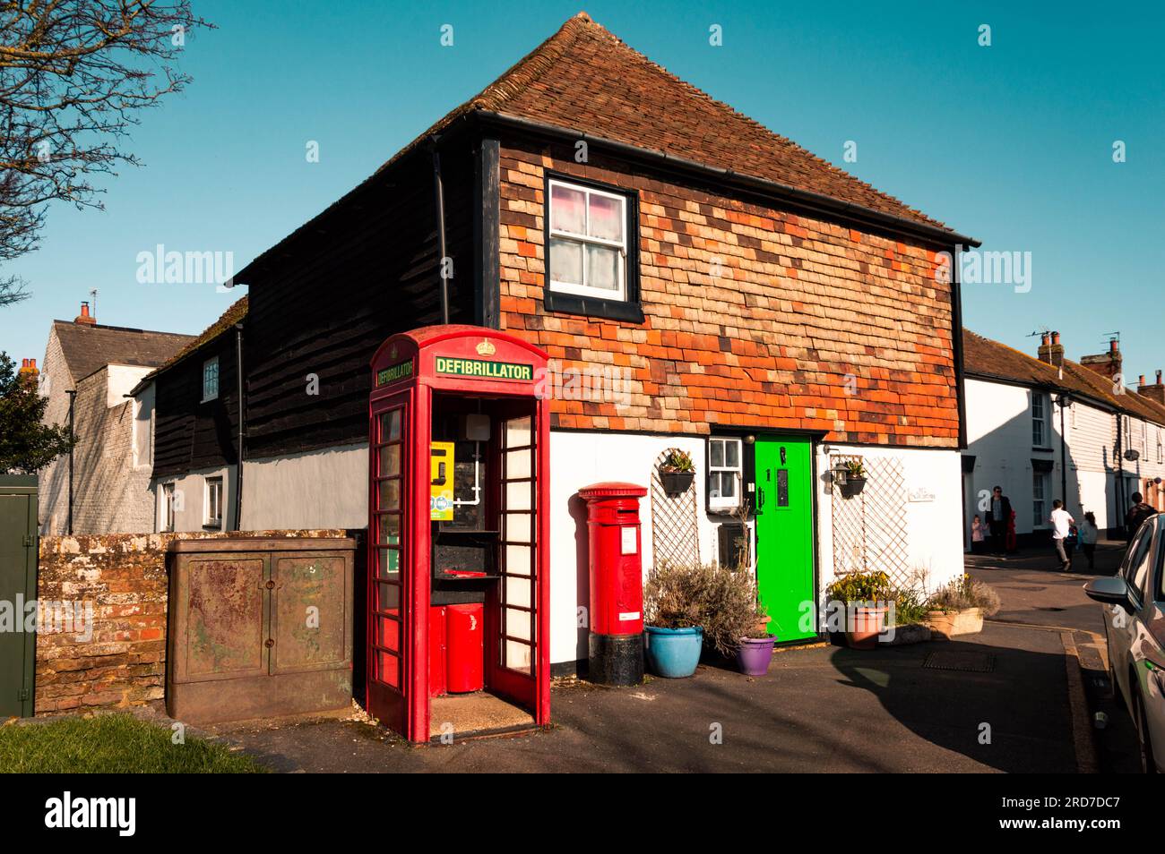 A Defibrillator Inside a Red Telephone Box Besides a House, Lydd, Kent, England Stock Photo