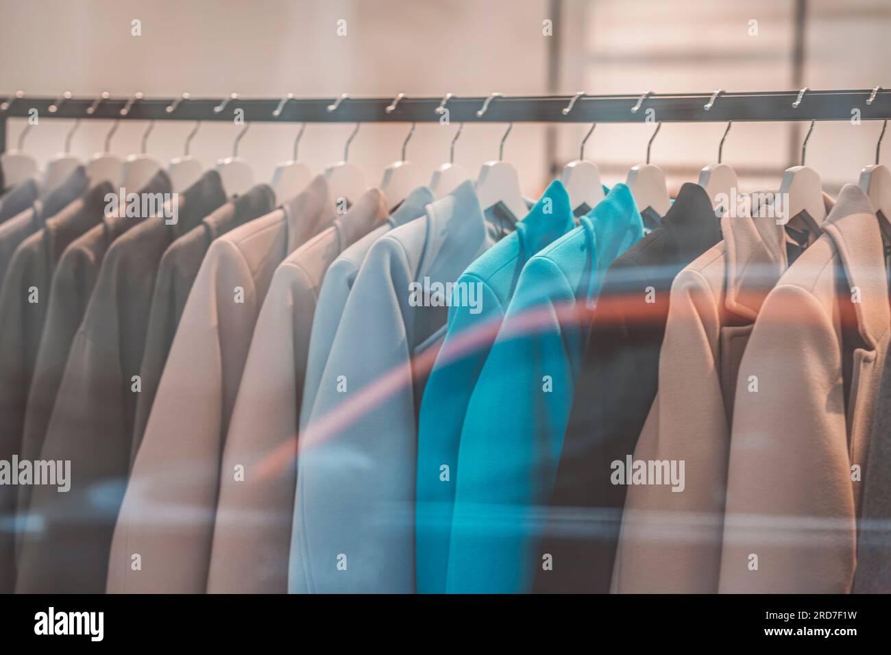 Elegant casual coats hanging on hanger in clothing store, blurred store interior. Store concept, sale Stock Photo