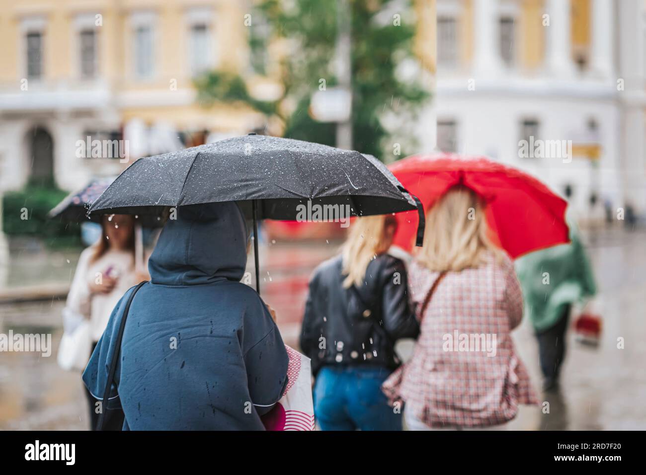 People under umbrellas. Rainy evening, city street at autumn. Seasons, weather concept. Abstract background Stock Photo