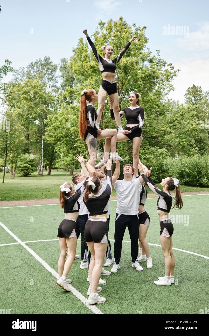 Vertical image of team of cheerleading training together with coach