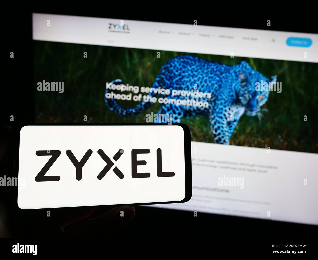 Person holding smartphone with logo of company Zyxel Communications Corporation on screen in front of website. Focus on phone display. Stock Photo