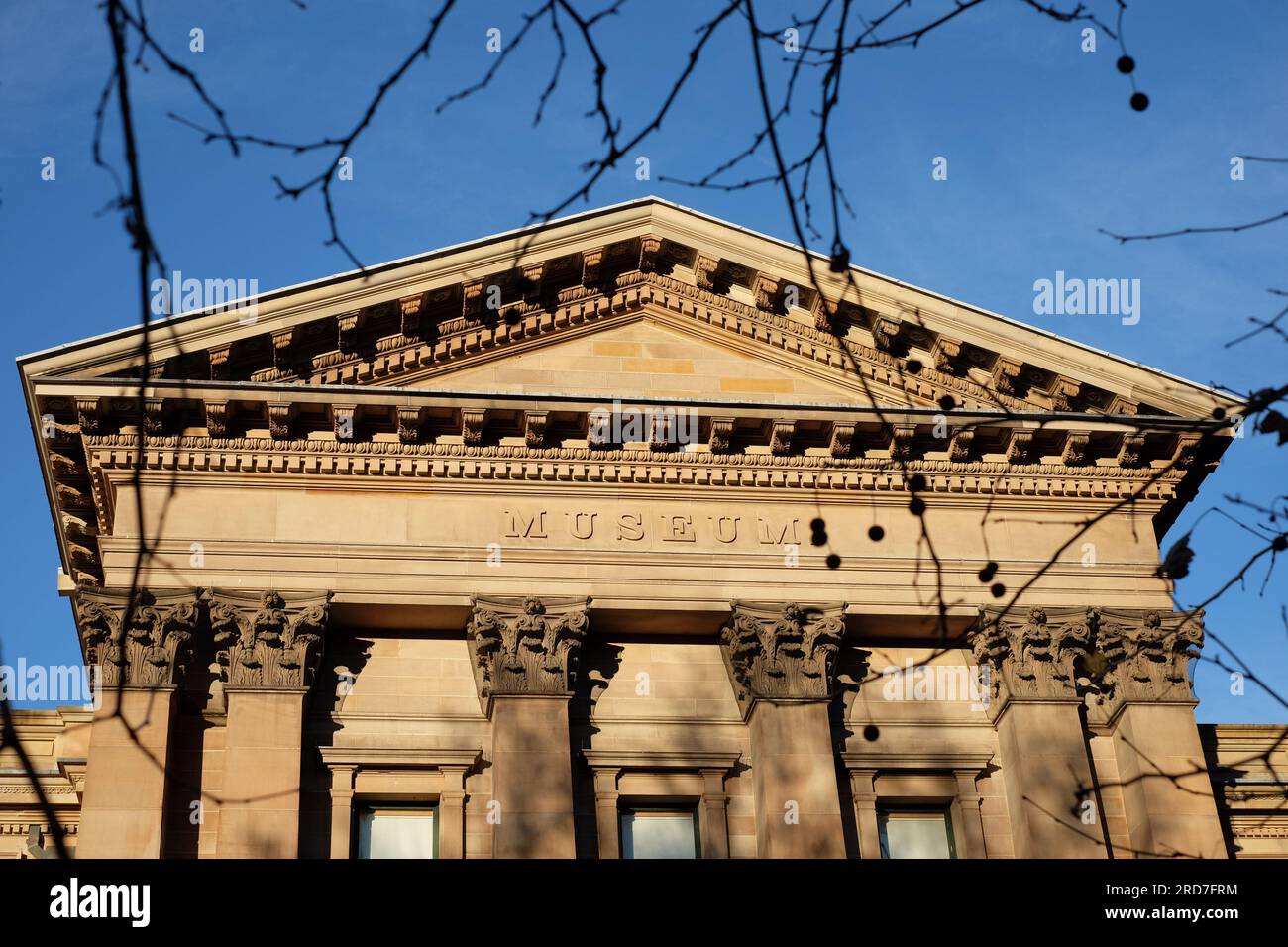 A view of the Greek Revival style Australian Museum tympanum, entablature and frieze featuring the word MUSEUM in high relief all in Sydney Sandstone Stock Photo