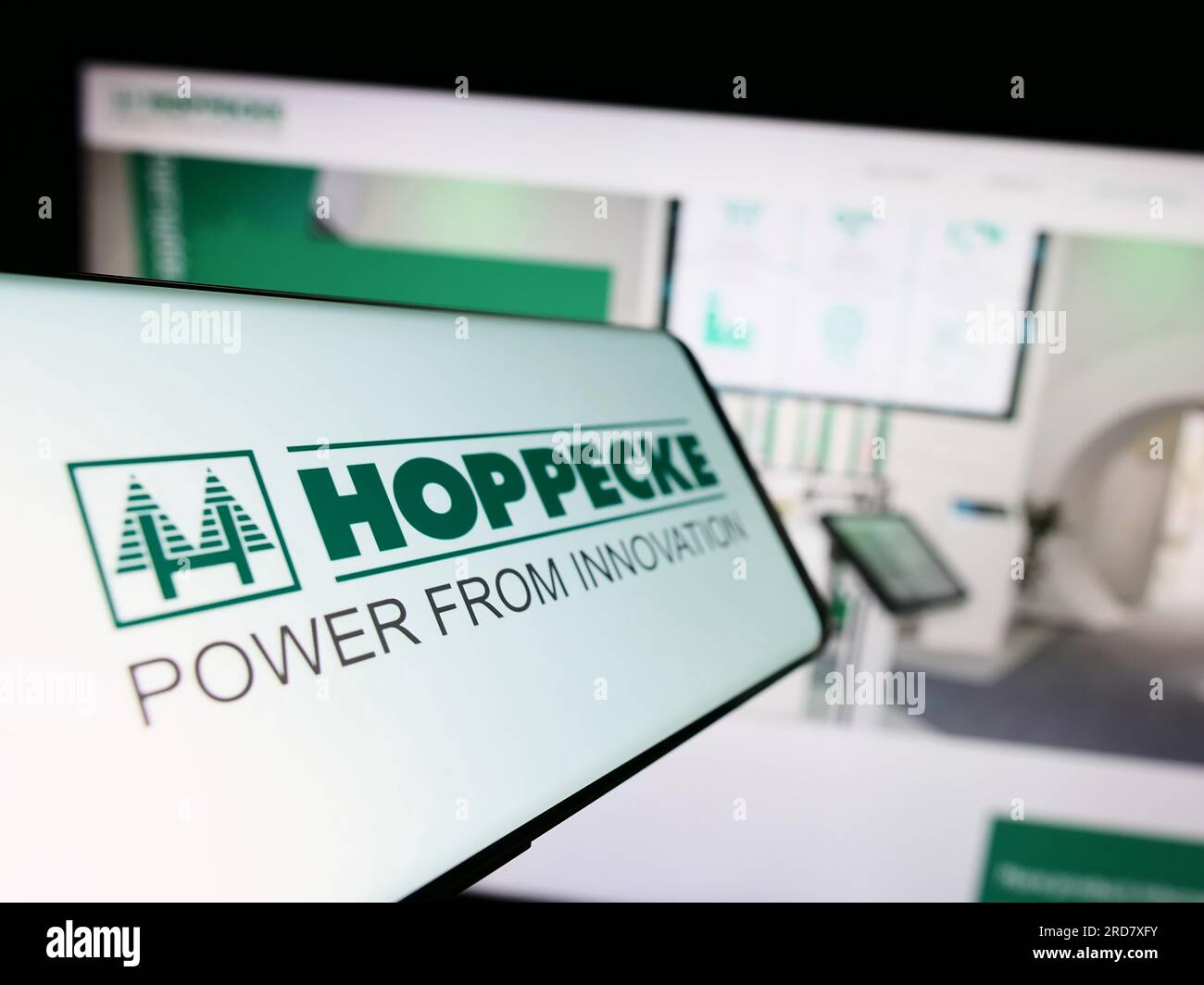 Cellphone with logo of German company Accumulatorenwerke Hoppecke on screen in front of business website. Focus on center-left of phone display. Stock Photo