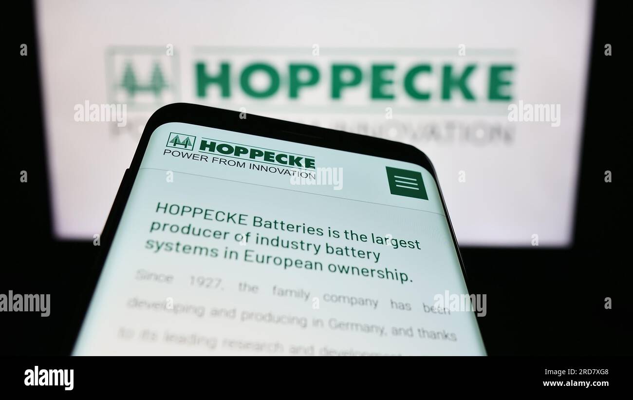 Mobile phone with website of German company Accumulatorenwerke Hoppecke on screen in front of business logo. Focus on top-left of phone display. Stock Photo