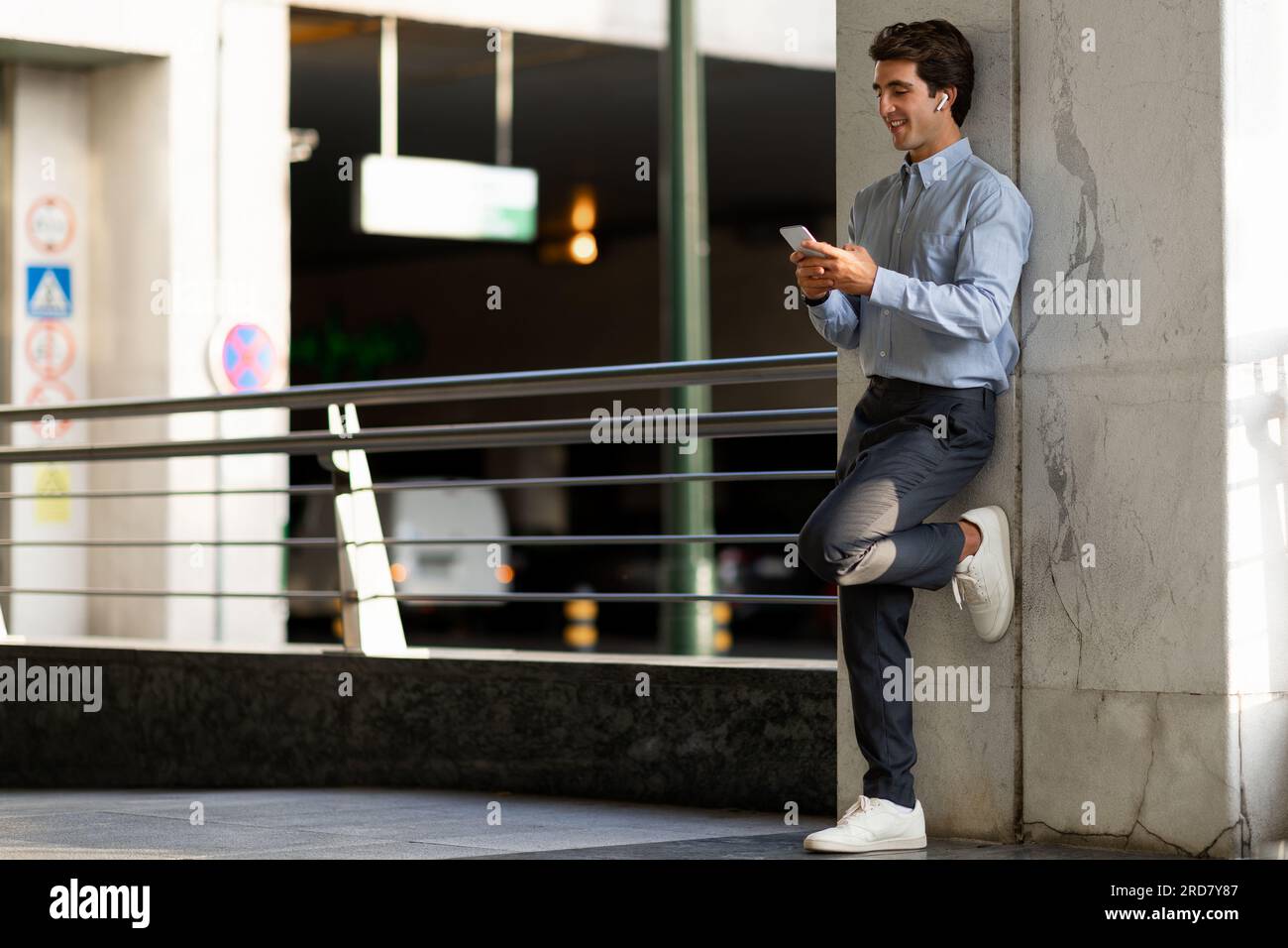 Young guy software engineer using smartphone and earbuds Stock Photo