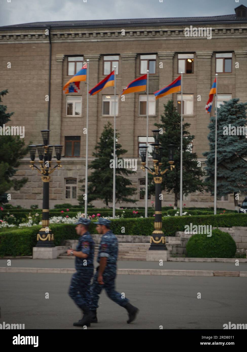 Two soldiers seen walking past a row of Karabakh flags lining outside the Presidential Building in Stepanakert, Nagorno-Karabakh. The unrecognised yet de facto independent country in South Caucasus, Nagorno-Karabakh (also known as Artsakh) has been in the longest-running territorial dispute between Azerbaijan and Armenia in post-Soviet Eurasia since the collapse of Soviet Union. It is mainly populated by ethnic Armenians. Stock Photo