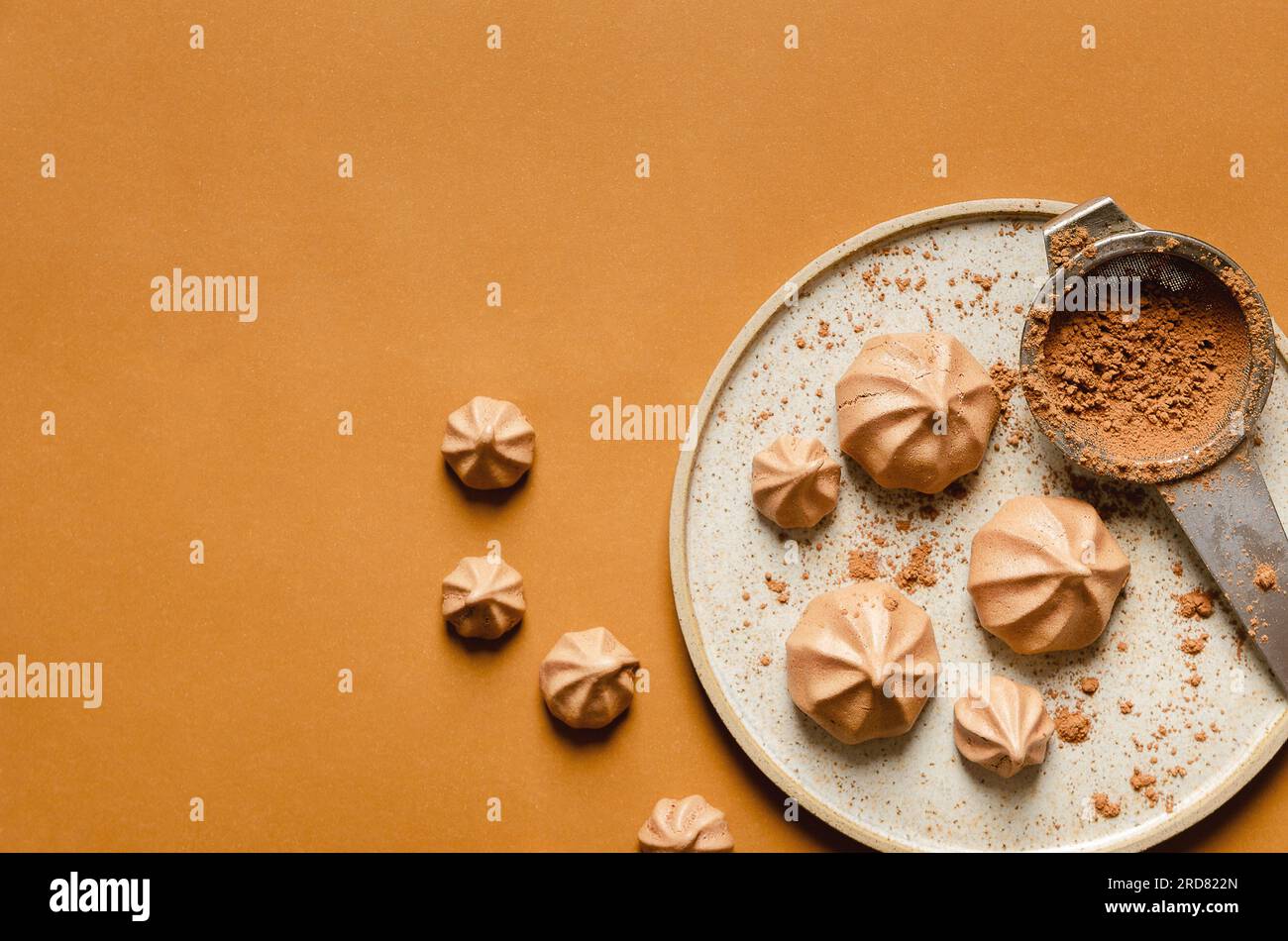 Chocolate meringue cookies and cocoa powder on a plate on a brown background Stock Photo Alamy