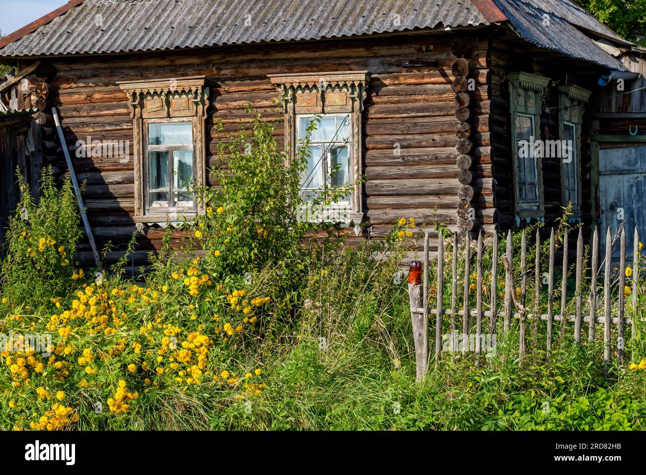 Old rustic log house and picket fence in the countryside, beautiful pastoral view Stock Photo