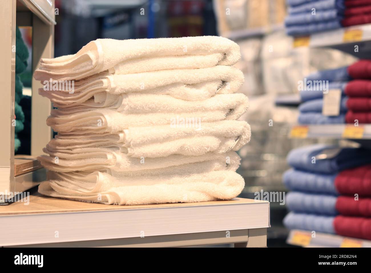 White towels folded in a pile in a store close-up. Home textile beautiful towels stacked on a shelf in a store Stock Photo