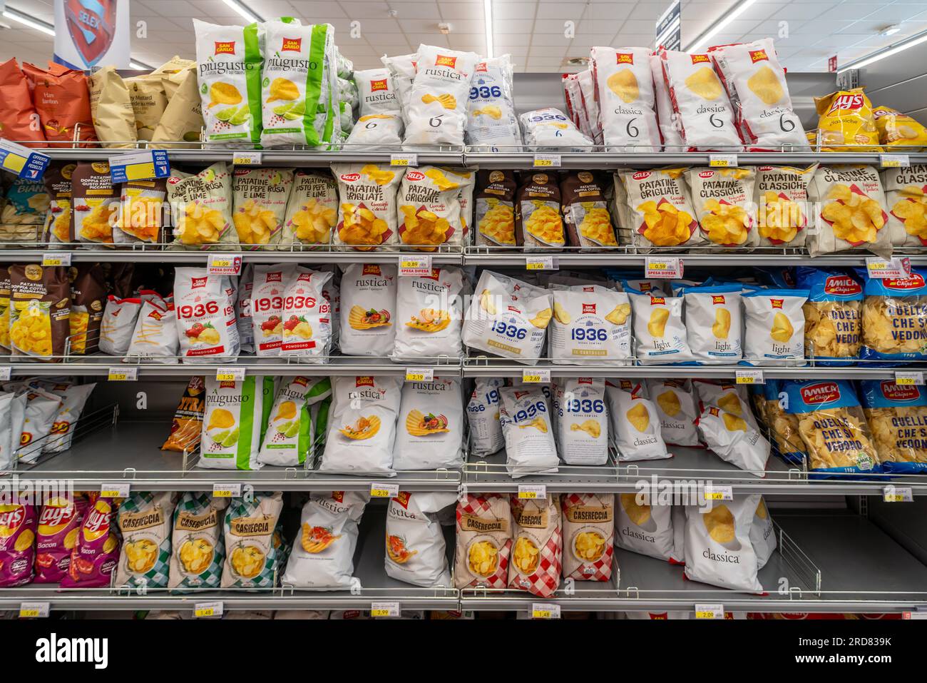 Italy - July 17, 2023: Potato chips in bags of various types and brands displayed on the shelf for sale in an Italian supermarket Stock Photo