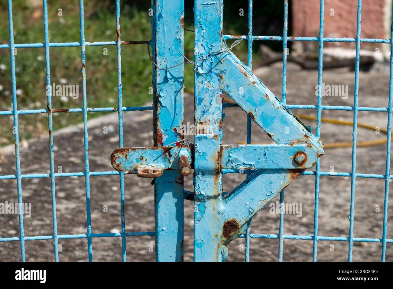 Detail of locking area of industrial exterior gates rusting through blue paint Stock Photo