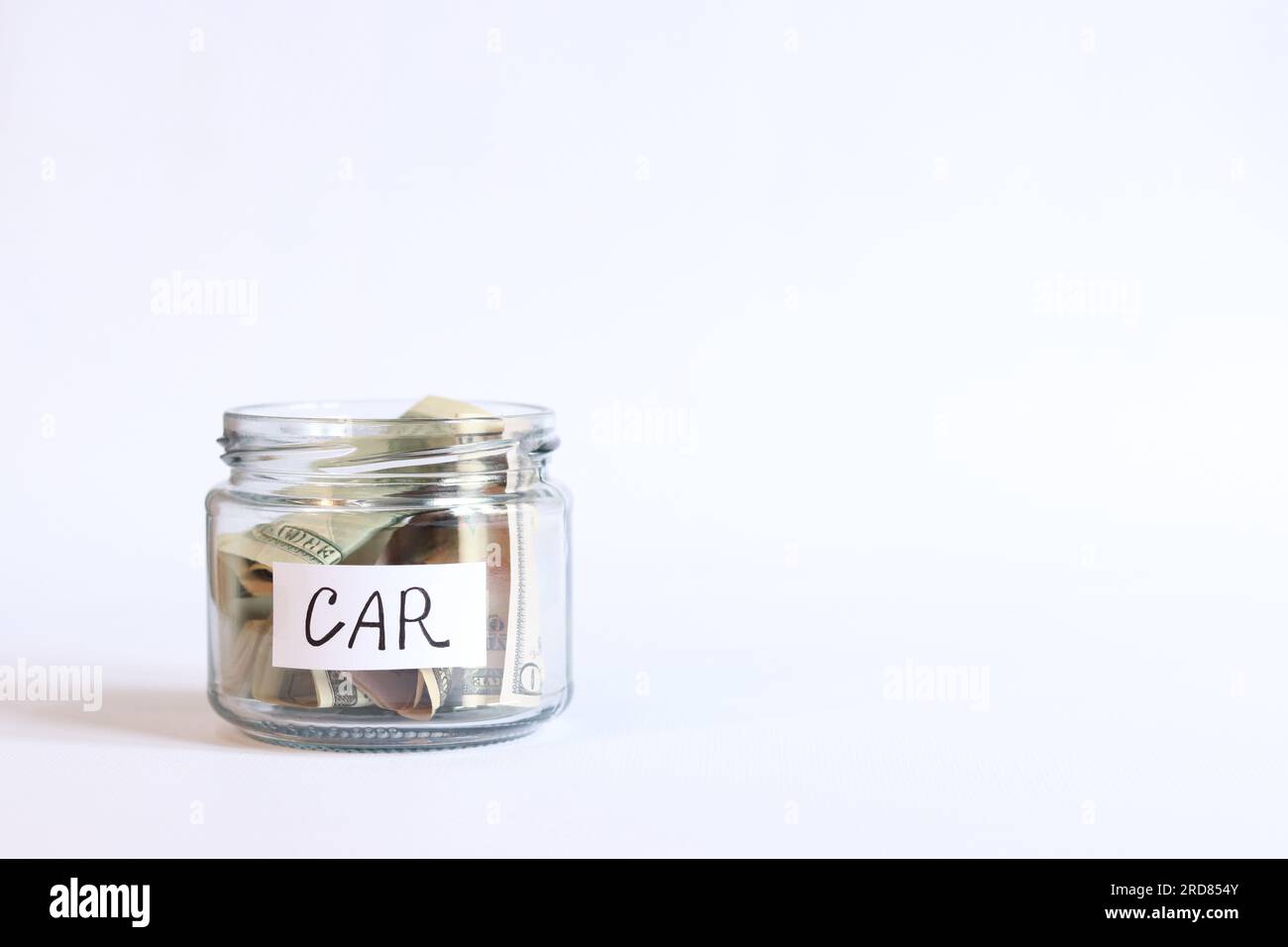 Glass jar with money close-up on a white background. Piggy bank with dollars for the car. Save money for the future Stock Photo