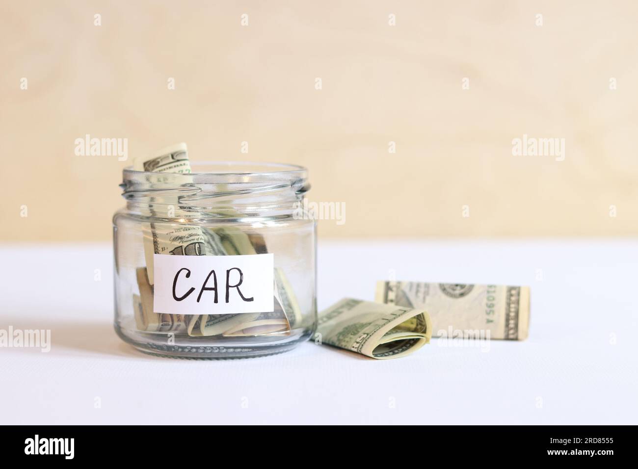 A glass jar with dollar bills inside and next to it. Bank with money close-up. Piggy bank with dollars for the car. Save money for the future Stock Photo