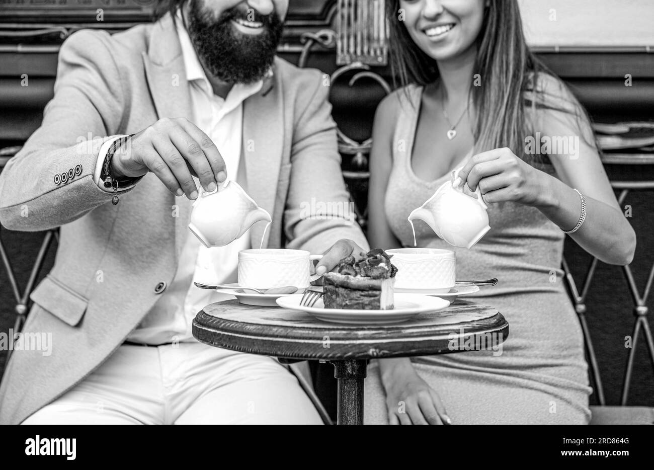Happy romantic couple sitting in a cafe drinking coffee. Young couple drinking cappuccino at bar coffee shop. Black and white Stock Photo