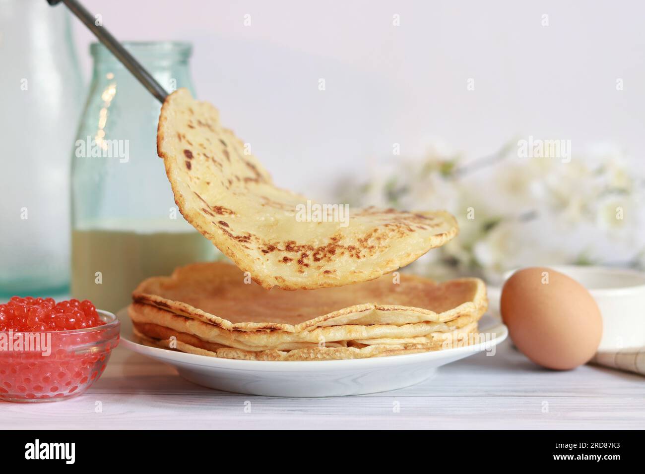 A stack of hot pancakes. Put a new crepes on a stack of ready-made pancakes. Large round thin pancake. Pancake week. Maslenitsa Stock Photo