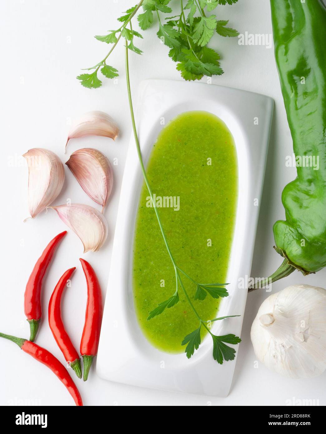 Top view of a bowl of salsa verde with ingredients: cilantro, chili peppers, bell pepper and garlic Stock Photo