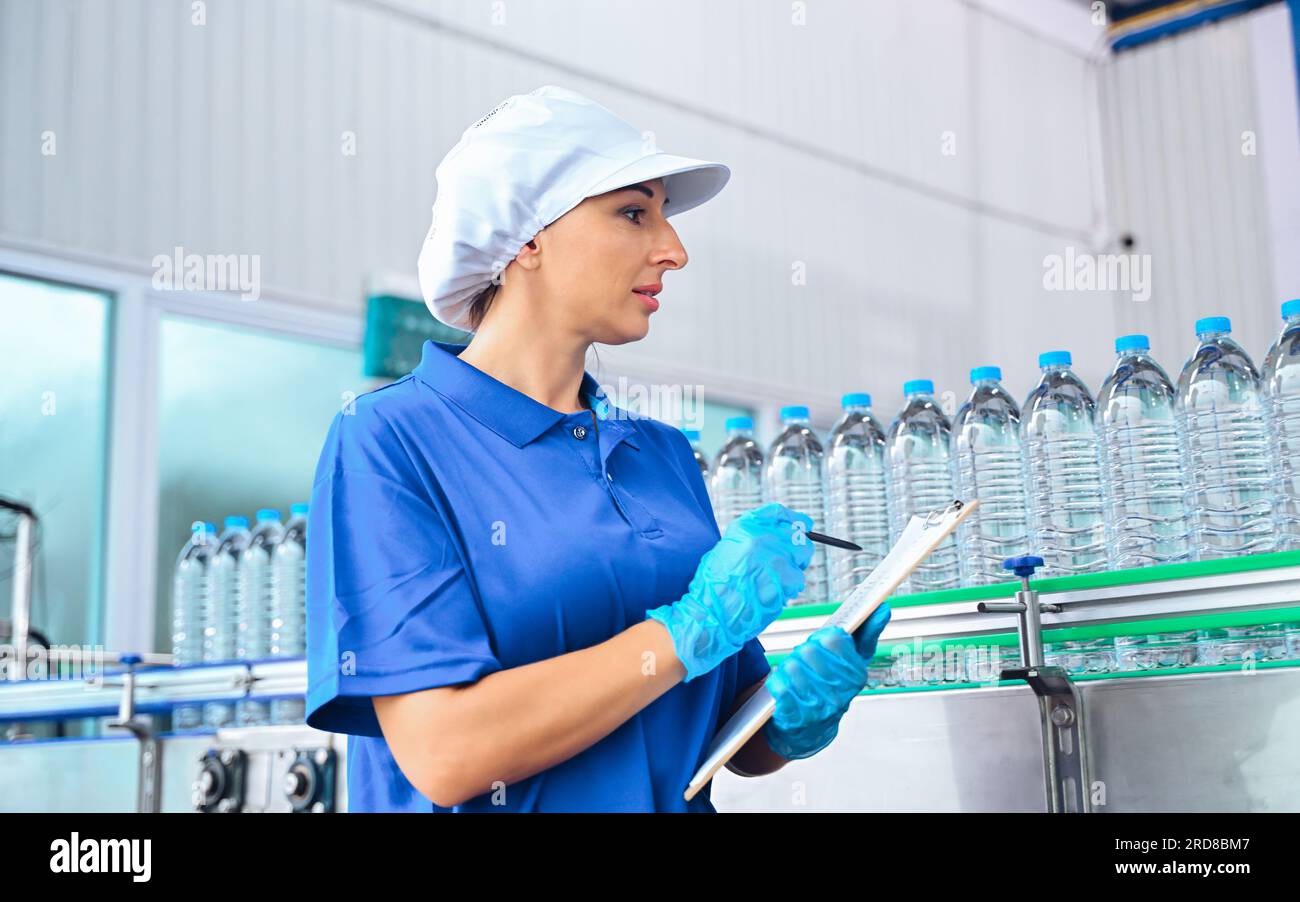 Bottling factory worker inspecting quality of water bottles before