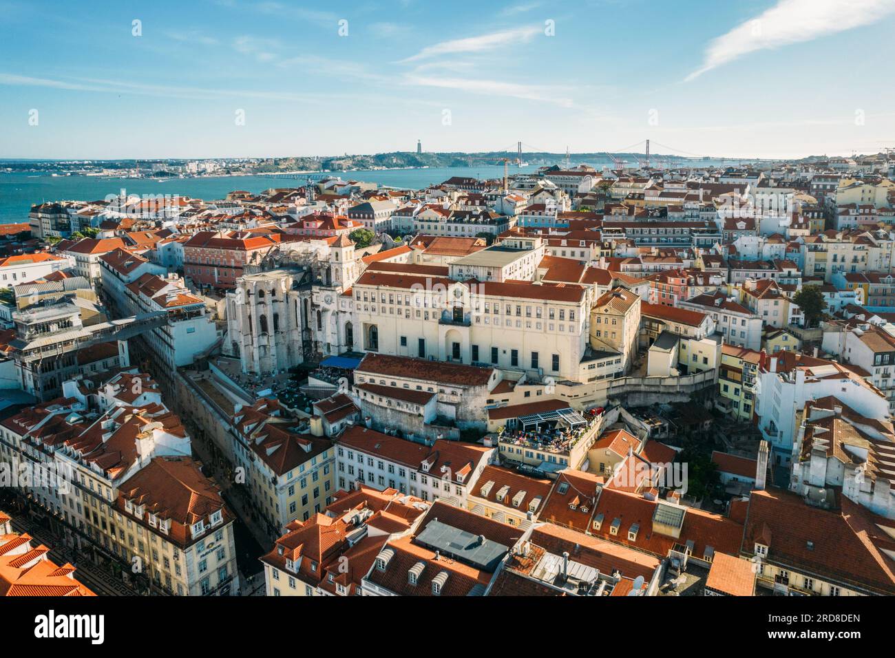 Aerial drone view of Carmo Church and surrounding historic neighbourhood in Chiado, with Tagus River and 25 April Bridge visible, Lisbon, Portugal Stock Photo
