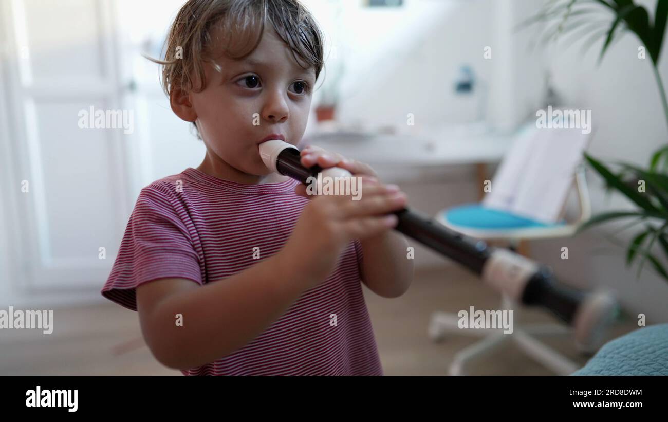 Child playing flute musical instrument toddler plays flute Stock Photo