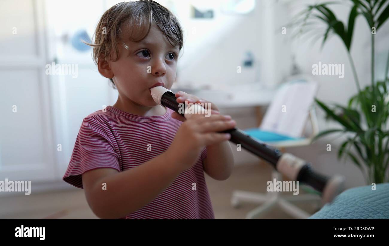 Child playing flute musical instrument toddler plays flute Stock Photo