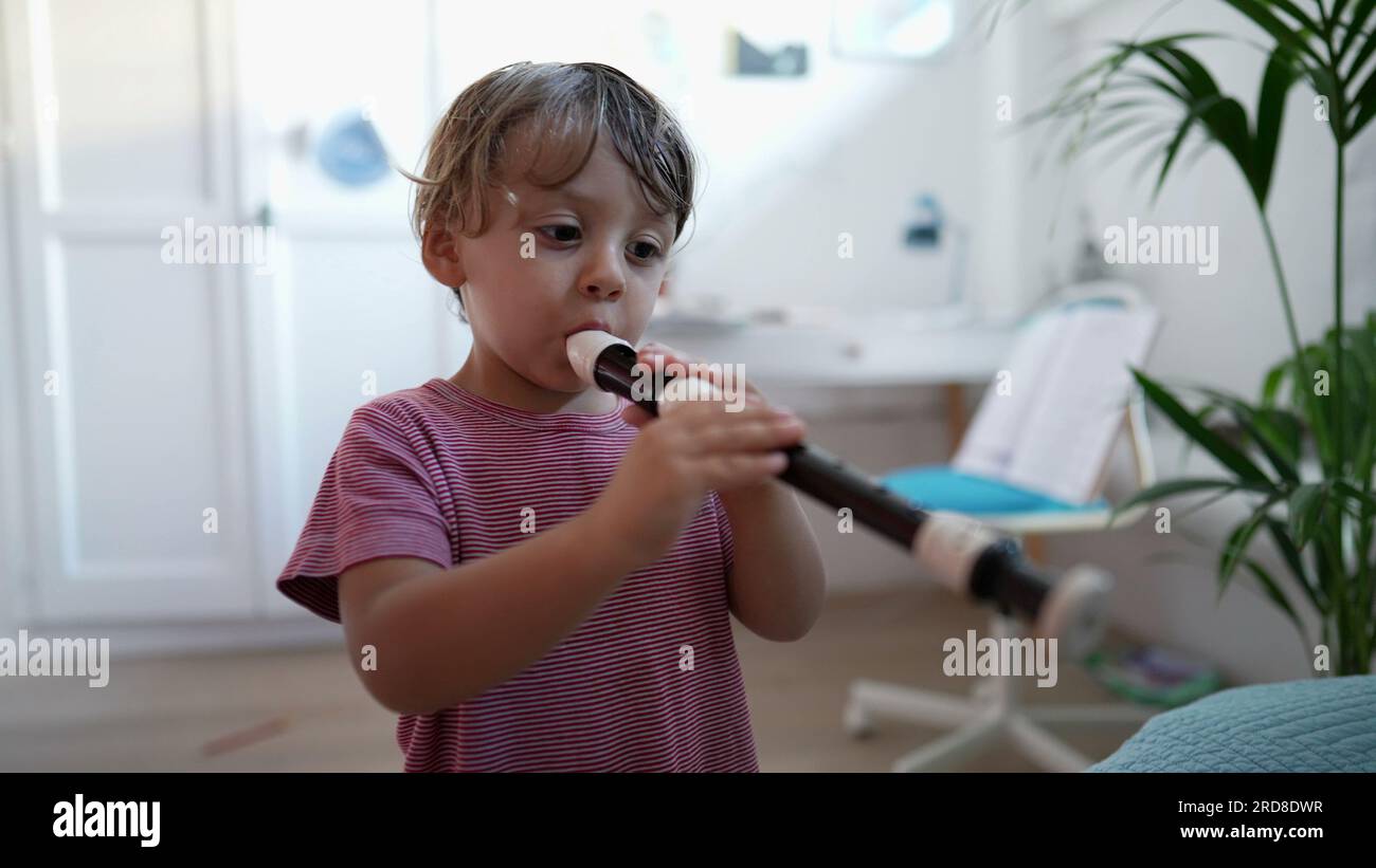 Child playing flute musical instrument toddler plays flute Stock Photo