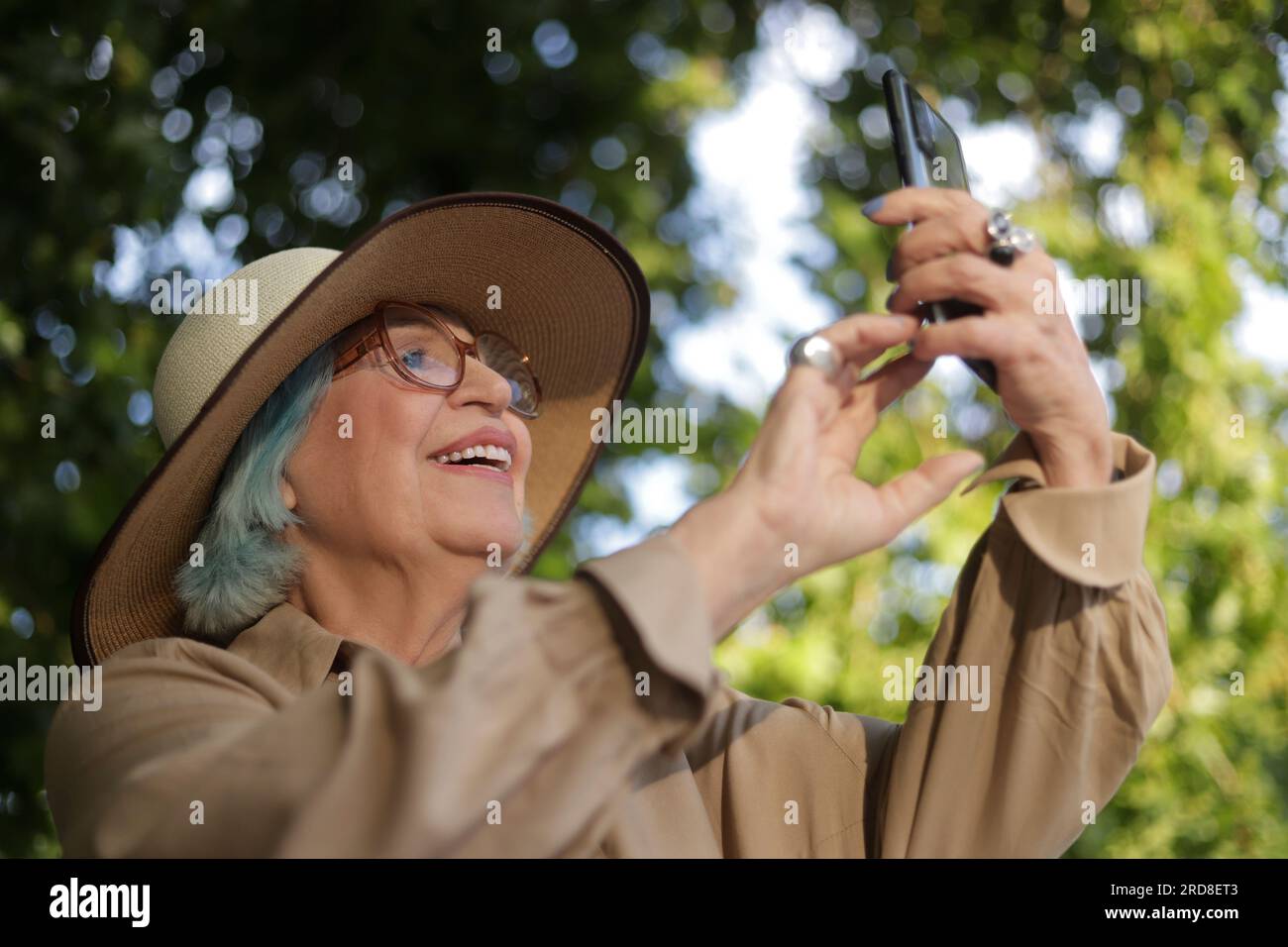 older woman outdoors with cell phone in hand Stock Photo