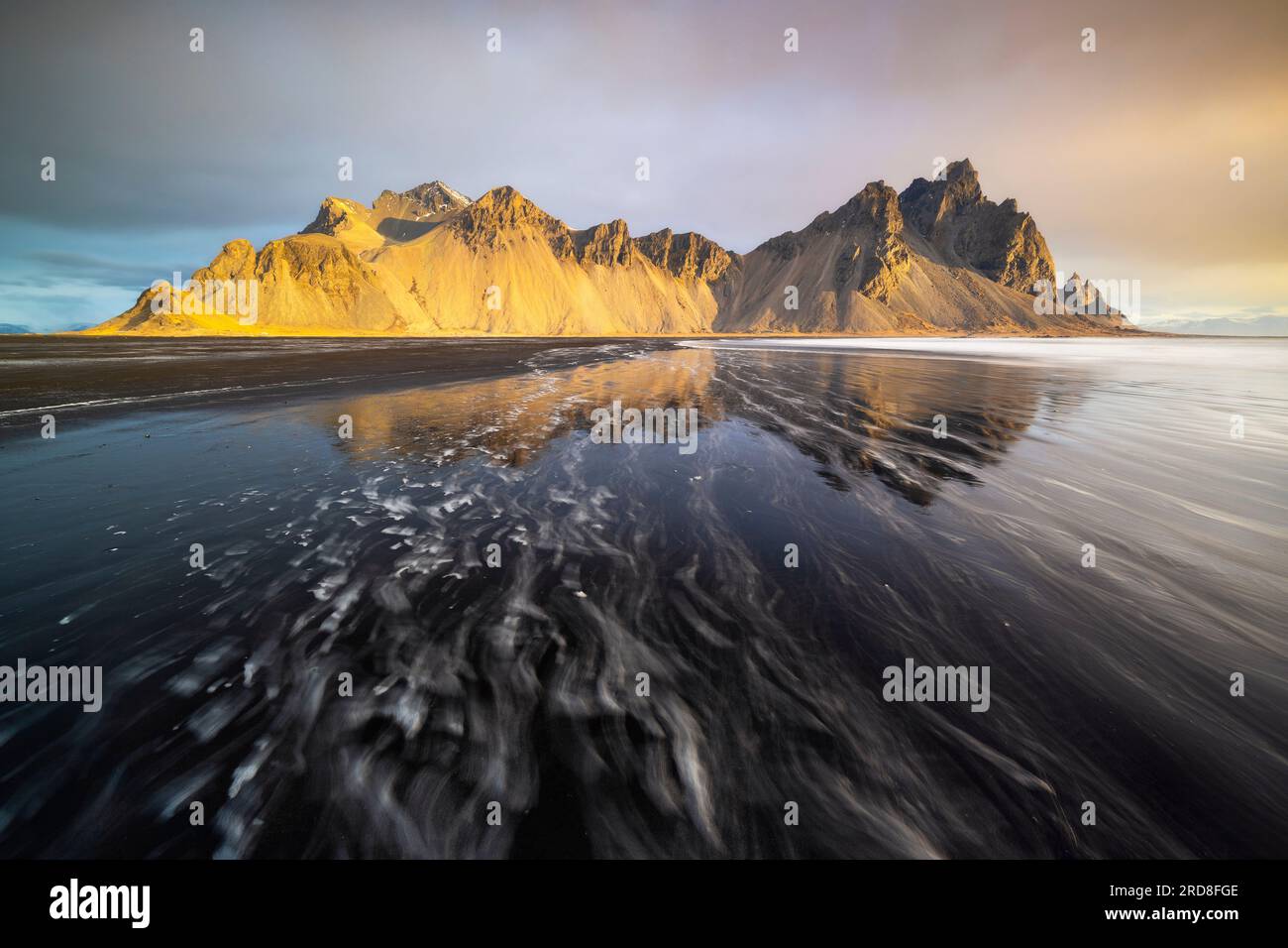 reflection-of-vestrahorn-mountain-over-black-sand-at-sunrise-in-spring