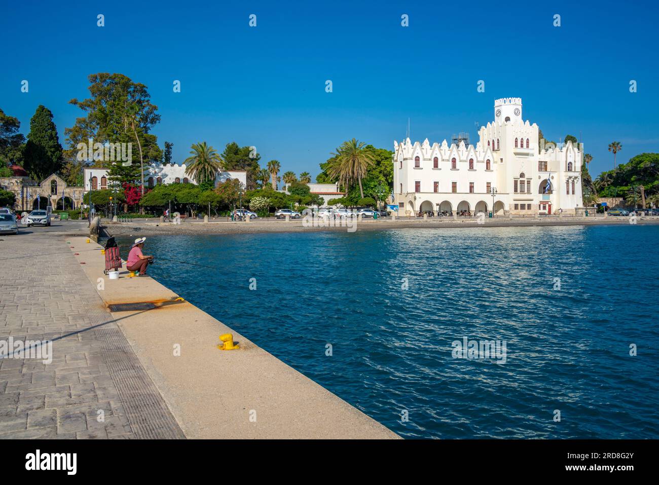 View of man fishing and County Government Office, Kos Town, Kos, Dodecanese, Greek Islands, Greece, Europe Stock Photo