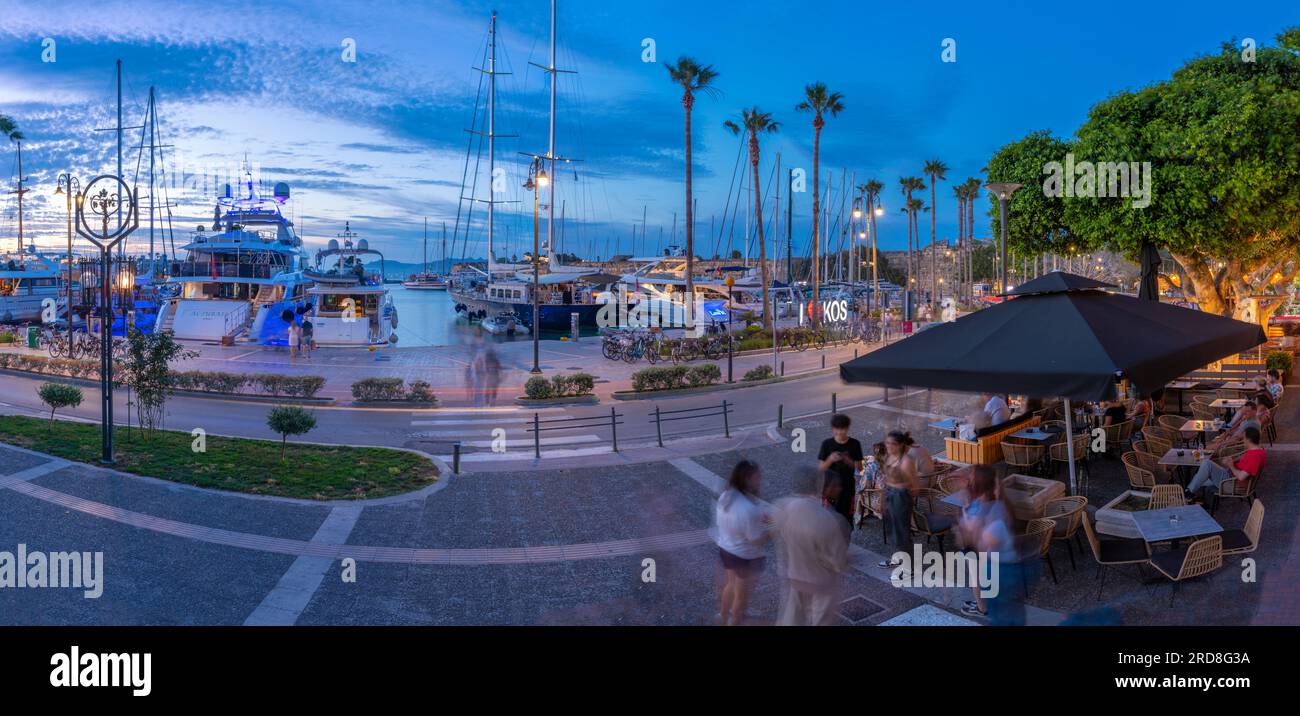 View of cafes and boats in Kos Harbour at dusk, Kos Town, Kos, Dodecanese, Greek Islands, Greece, Europe Stock Photo