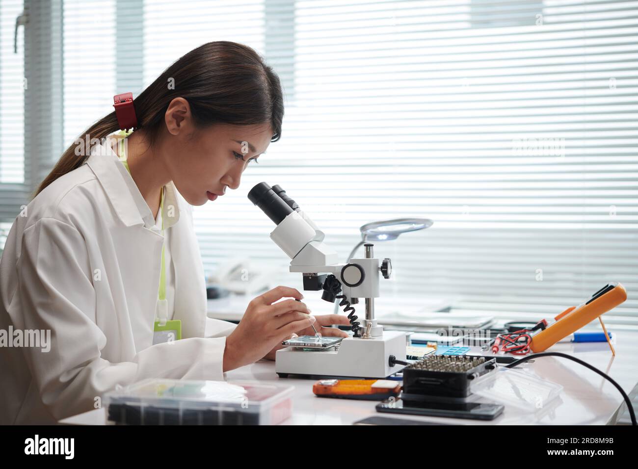 Engineer looking through microscope when repairing computer hard drive