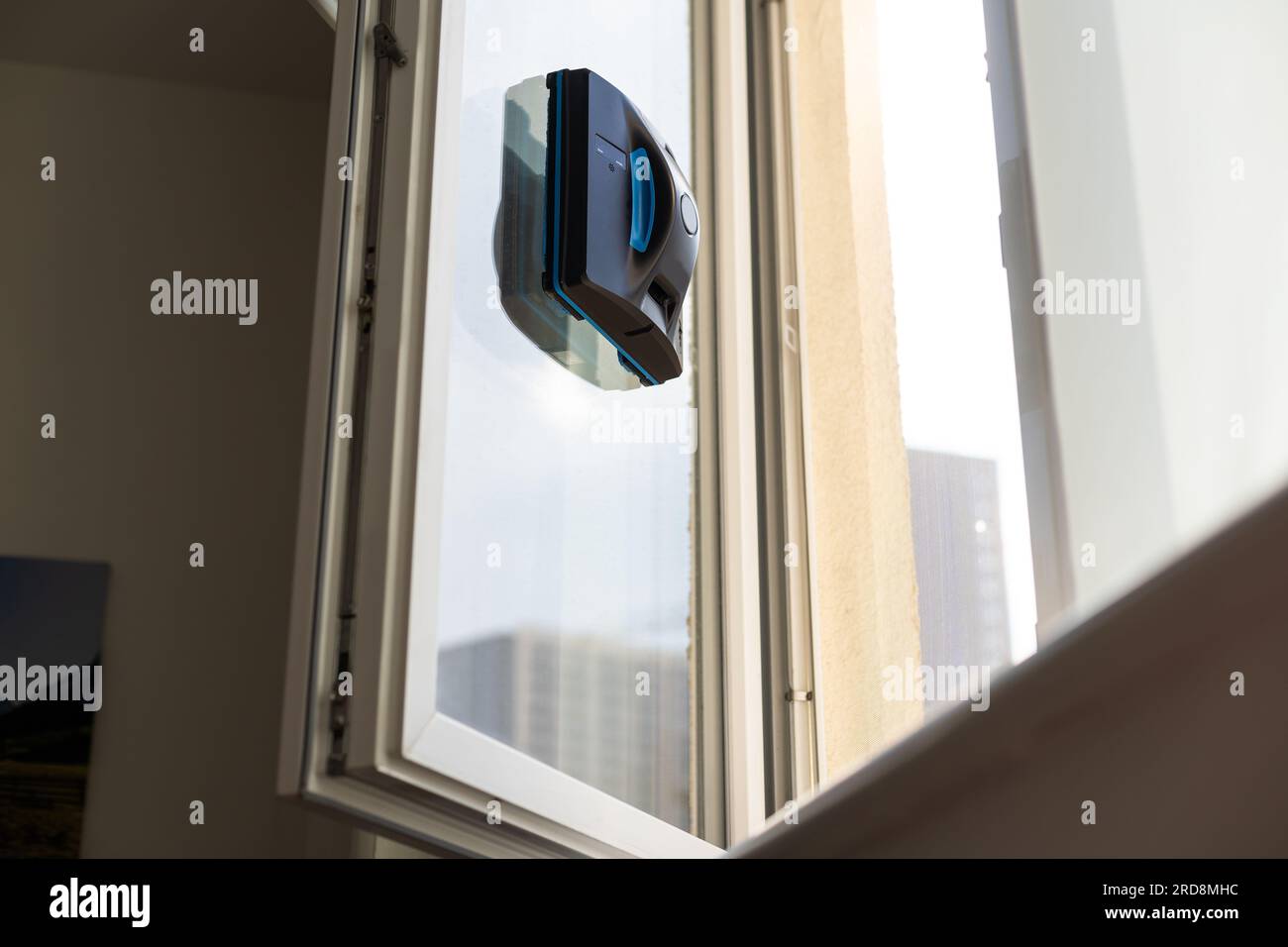 The white robotic window cleaner uses a brush and vacuum for a thorough