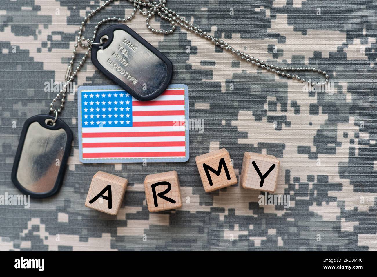 Military ID tags and US army patches on camouflage background, flat lay