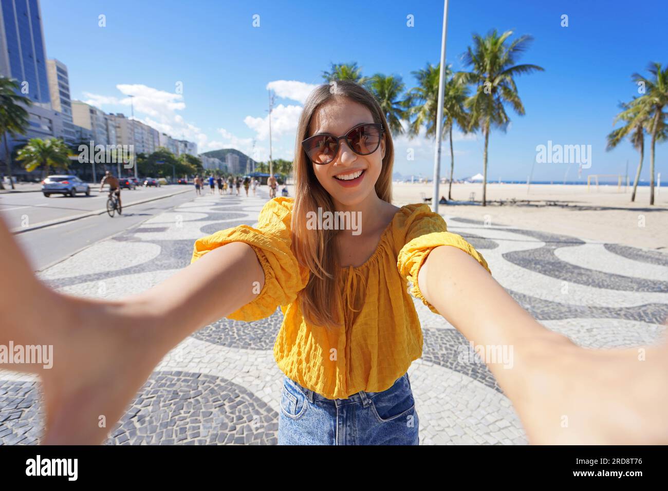 Tourism in Rio de Janeiro. Beautiful smiling girl takes self portrait on Copacabana beach promenade, Rio de Janeiro, Brazil. Stock Photo