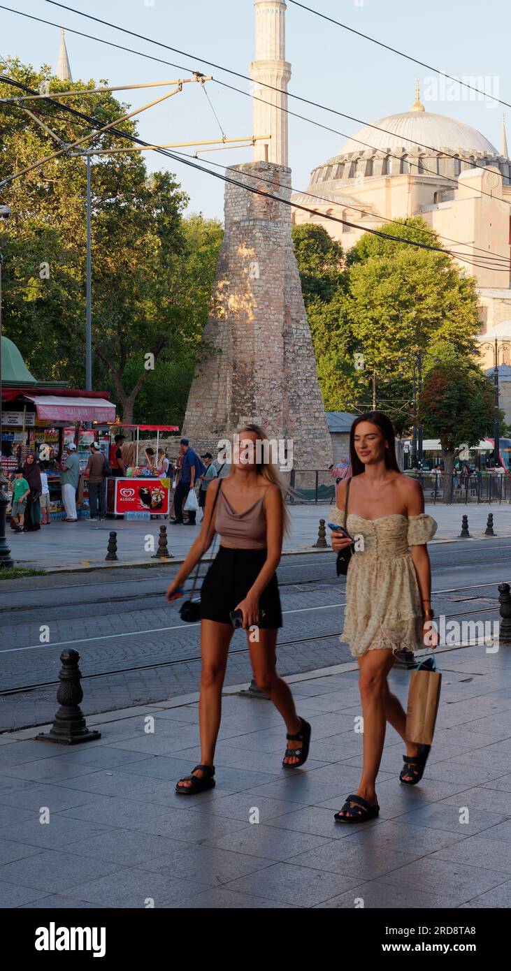 Two young woman smile on a street in Sultanahmet on a summers evening with the Hagia Sophia Mosque behind, Istanbul, Turkey Stock Photo