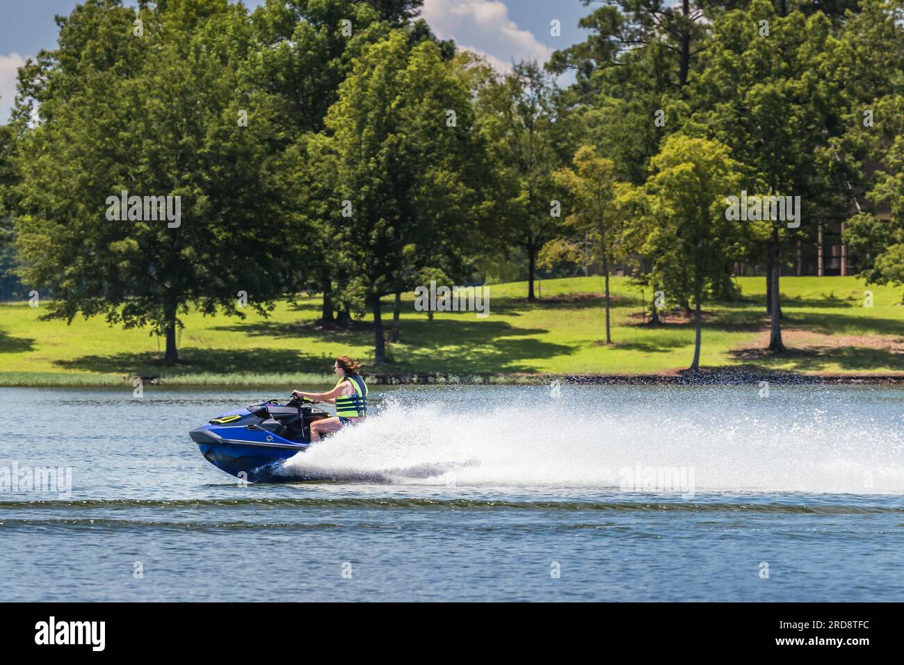 Lady riding jet ski and enjoying summer day on Lake Oconee, Georgia. Riding personal watercraft is a popular form of water recreation. Stock Photo
