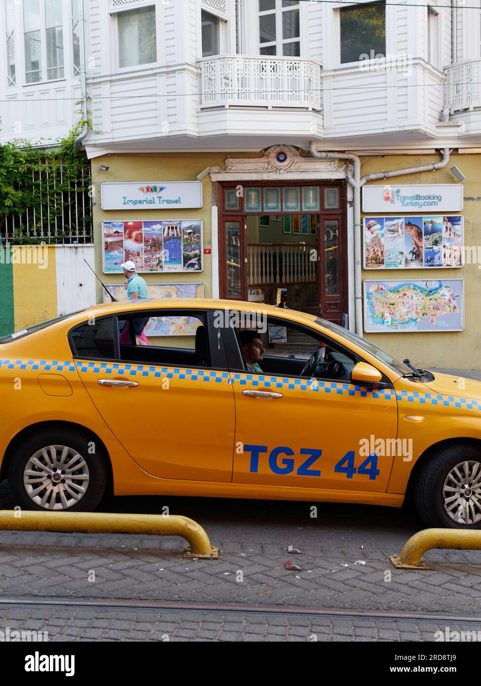 Yellow Taxi and Driver parked on a road in Istanbul Turkey with a travel agency behind. Stock Photo