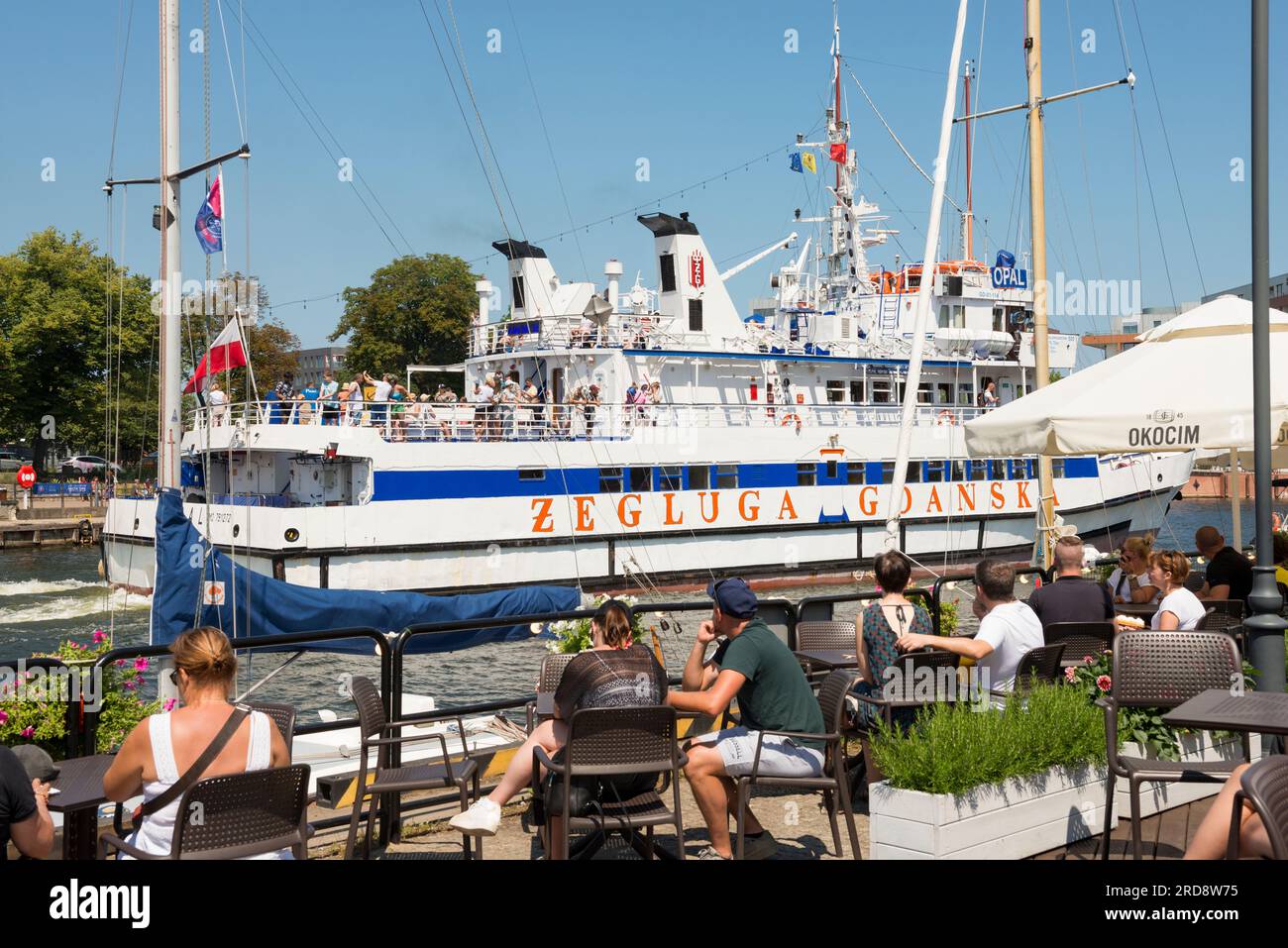 Zeluga Gdanska cruise ship in Motlawa River passing by alfresco dining tourists in the Old Town of Gdansk, Poland, Europe, EU Stock Photo